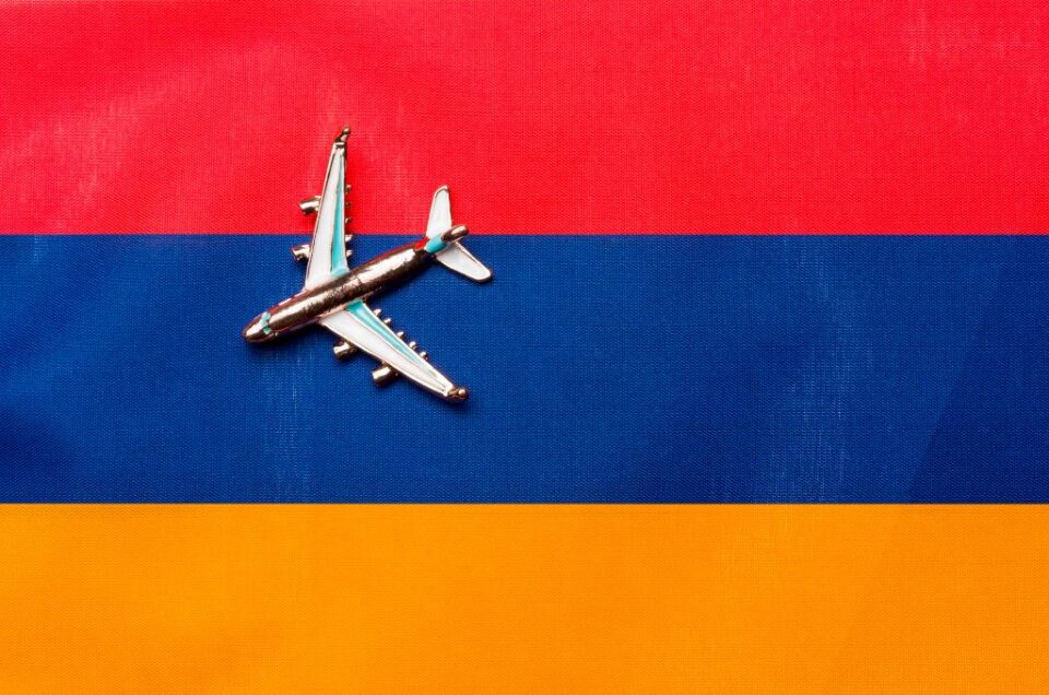 Bandera de Armenia y un pequeño avión plateado encima mostrando Vuelos de Madrid a Armenia